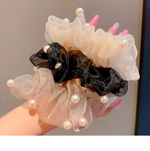 Detail of elegant organza scrunchies with pearls in black, beige, and champagne colors