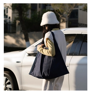 Lifestyle shot of large dark blue nylon shoulder bag worn by model on street