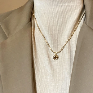 Close-up of golden bamboo-style necklace with a round brown gemstone on a model