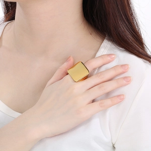 Close-up of oversized gold square titanium ring worn on index finger for scale and style