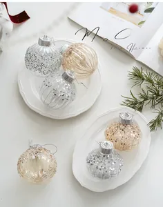 Close-up of champagne and silver Christmas balls with vertical stripes and sequins