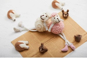 Detailed view of handmade felted wool sheep dolls with corgi butt accessories on newspaper