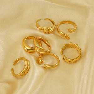 Set of 7 gold irregular stainless steel rings on elegant champagne satin fabric