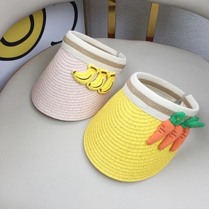 Close-up of yellow and pink woven straw sun hats for kids with cute fruit decorations