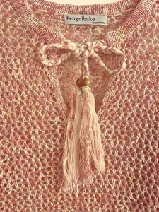 Detailed close-up of hollow crochet knit top with V-neck lace-up tassel and wooden beads