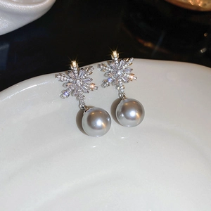 Macro shot of sparkling zircon snowflake earrings with elegant grey pearl pendants