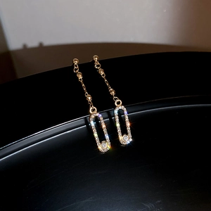 Detailed close-up of golden tassel earrings with sparkling rhinestones on black background
