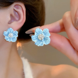 Gros plan de boucles d'oreilles fleurs en émail bleu clair avec strass étincelants