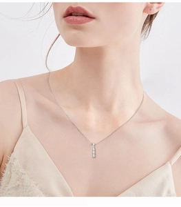 Detail of S925 sterling silver necklace with three vertical diamonds on female model