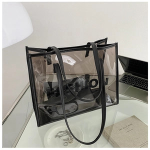 Translucent smokey gray PVC tote bag with black trim in a minimalist desktop setting