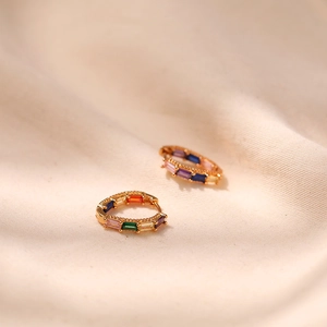 Macro detail of 18K gold plated huggie earrings with rainbow baguette-cut gemstones