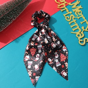 Detail of a Christmas themed black satin scrunchie with ribbons and festive decorations