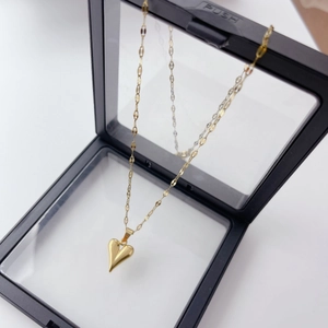 Detail of a shiny gold 3D heart pendant necklace displayed in a black jewelry box