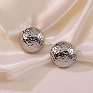 Polished silver hammered hemispherical earrings set on soft white satin fabric