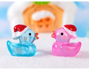 Close-up of translucent pink and blue resin Christmas ducks with festive red hats