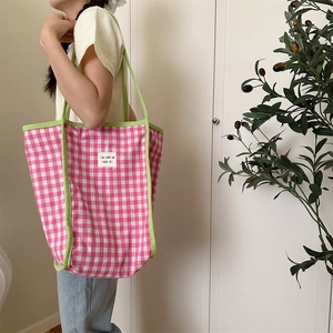 Detailed side view of a large checkered canvas tote bag with pink pattern and green piping