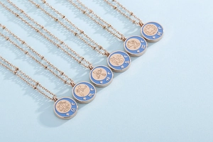 Detail of rose gold zodiac coin pendants with light blue enamel on beaded chains