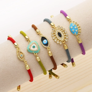 Bracelets colorés en nylon avec pendentifs œil porte-bonheur dorés sur support à bijoux