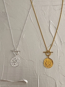 Detail showing gold and silver coin necklaces with toggle clasps and textured pendants
