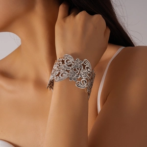 Detailed close-up of intricate silver filigree hollow floral pattern on a wide cuff bracelet
