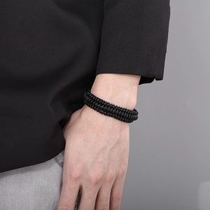 Close-up of a men's multilayer braided leather bracelet with stainless steel clasp