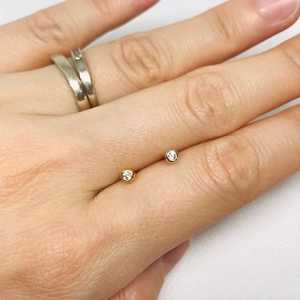 Detailed view of small round cubic zirconia stud earrings in gold and silver finish