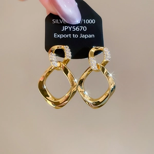 Detail view of twisted rhombus drop earrings with gold finish and sparkling zircon stones