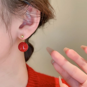 Close-up of elegant gold and red double bead earrings worn by a model in a soft setting
