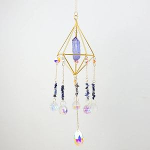 Detail of crystal suncatcher with gold wire frame, raw blue stone and rainbow prism drop