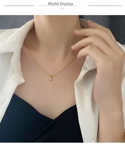 Detail shot of a pearl pendant necklace with a gold wavy chain on a model's neck