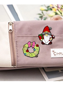 Close-up of Santa and wreath enamel pins with crystals on a purple canvas bag