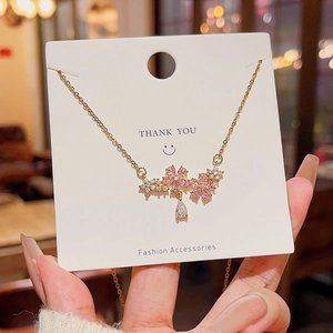 Detailed view of a gold bow necklace with cherry blossom pendant and pear-shaped zircon