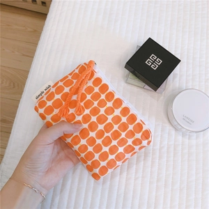 Close-up of small orange checkered canvas pouch with zipper and simple wish label