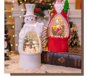 Detail view of Santa and snowman music box snow globes in a festive Christmas setting