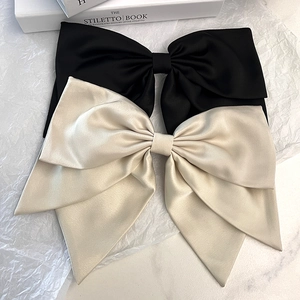 Close-up of large elegant black and cream satin bow hair clips on a marble surface