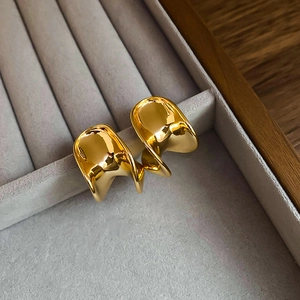 Detailed view of gold plated C-shaped twisted earrings in a grey velvet jewelry box