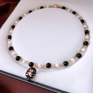 Luxury pearl and black bead necklace featuring a gold bear pendant on an enamel base