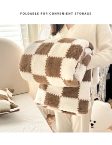 Detail showing the foldable design and plush texture of a brown checkerboard fleece blanket