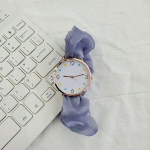 Macro shot of a purple silk scrunchie watch band with a white dial and golden bezel
