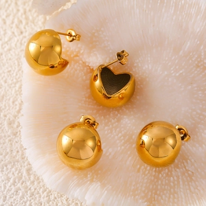 Minimalist gold-plated hollow spherical stud earrings on white coral texture background