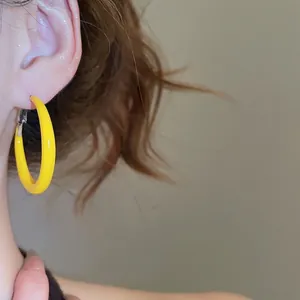 Boucles d'oreilles créoles jaunes en forme de C avec fermoirs argentés sur un modèle