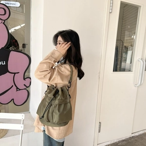 Army green nylon bucket bag with adjustable shoulder strap and drawstring closure for women