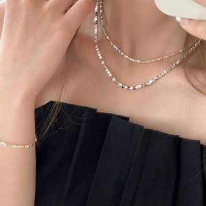 Détail d'un collier multicouche minimaliste à perles facettées argentées pour femme