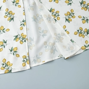 Detailed view of summer dress featuring lemon print and high-slit hem stitching