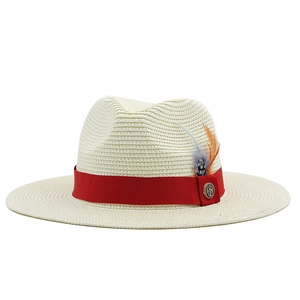 Straw fedora hat with red ribbon and anchor feather detail on a white background