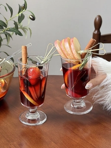 Detailed view of red mulled wine glass with fresh fruits and cinnamon stick garnish