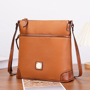 Detailed view of brown pebble leather crossbody bag with vintage brass hardware and zippers