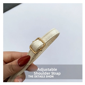 Detailed close-up of adjustable cream leather shoulder strap with gold metal buckle