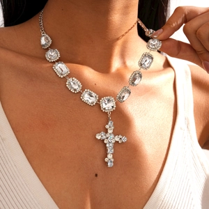 Close-up of a silver cross pendant necklace with large square and round rhinestones