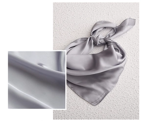 Close-up detail of smooth silk texture and sheen on a minimalist grey satin square scarf